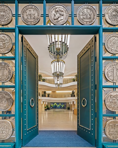 Porta de ferro verde com moedas em relevo na entrada do prédio da B3